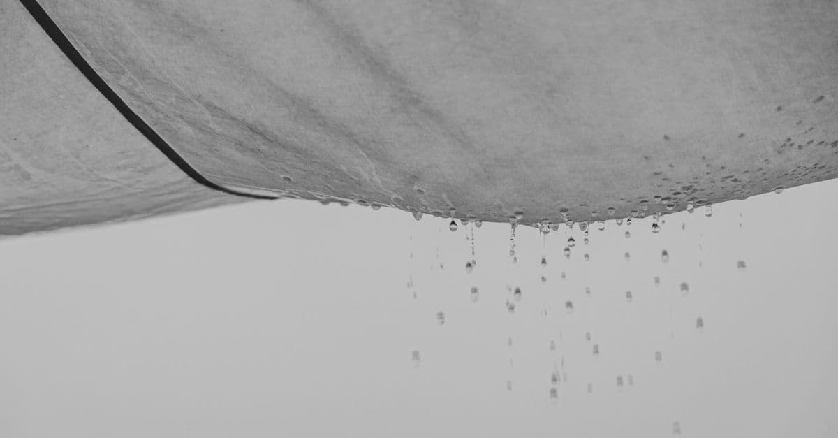 Black and white composition of water drops falling from rag material on gray background