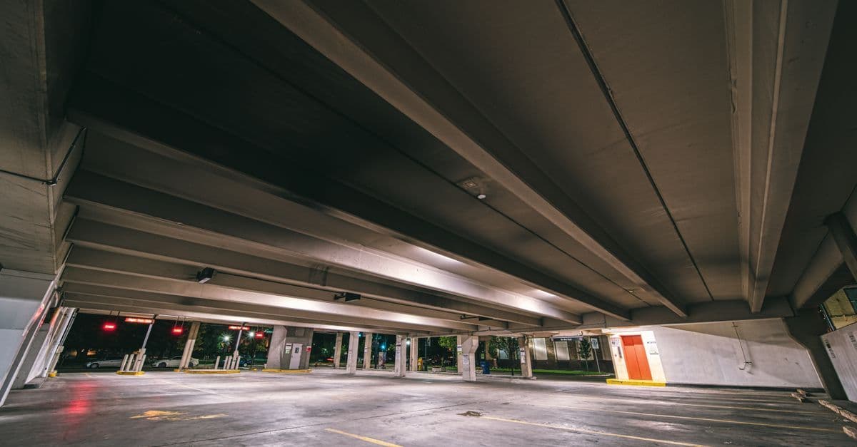 Entrance to underground parking with empty spaces under concrete roof at night time